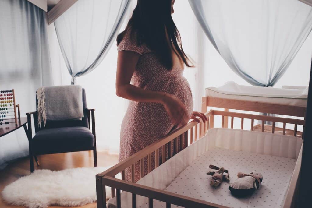 Femme enceinte devant le lit de son futur bébé